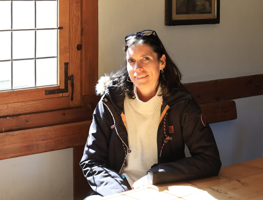 Portrait d'Amandine Devergies assise à une table en bois massif, éclairée par la lumière naturelle d'une fenêtre ancienne au Château d'Aigle.