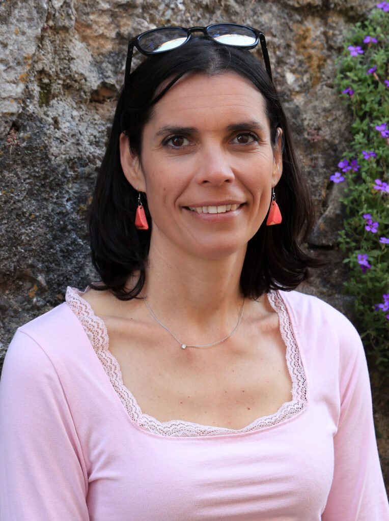 Portrait d'Amandine Devergies, accompagnante en divorce et séparation, souriante devant les murs en pierre du village de Saint-Saphorin.