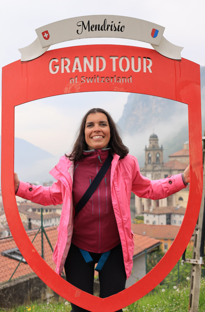 Amandine Devergies accompagnante divorce souriante devant le panneau Grand Tour of Switzerland à Mendrisio