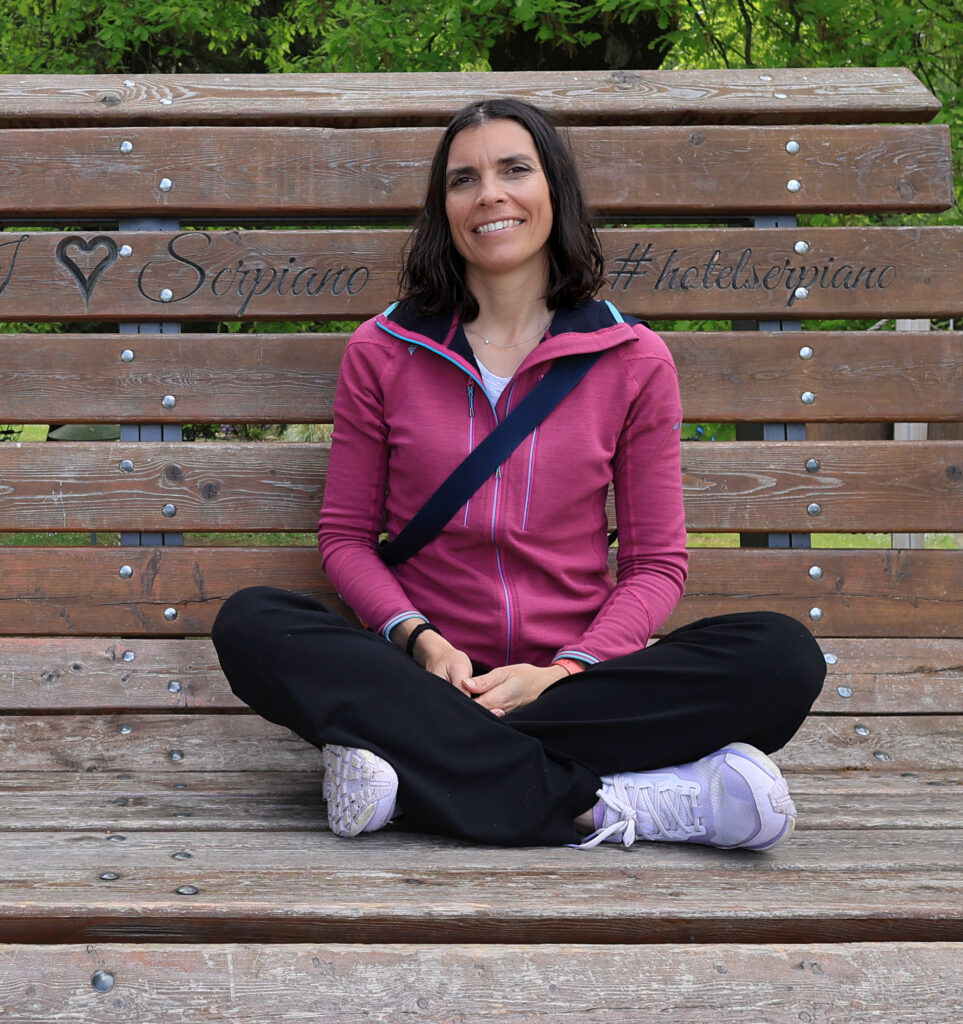 Amandine Devergies assise en tailleur sur un banc en bois, accompagnante Cap Clarté