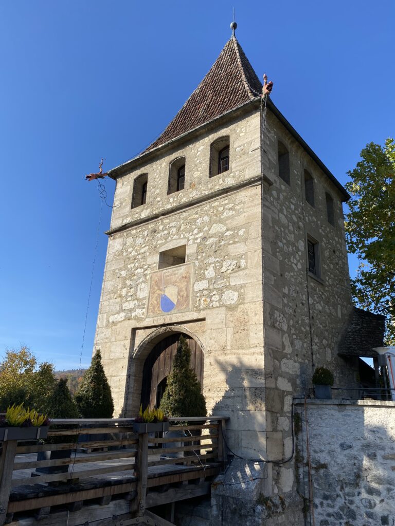 Tour-porte médiévale en pierre avec pont de bois, ciel bleu, Suisse