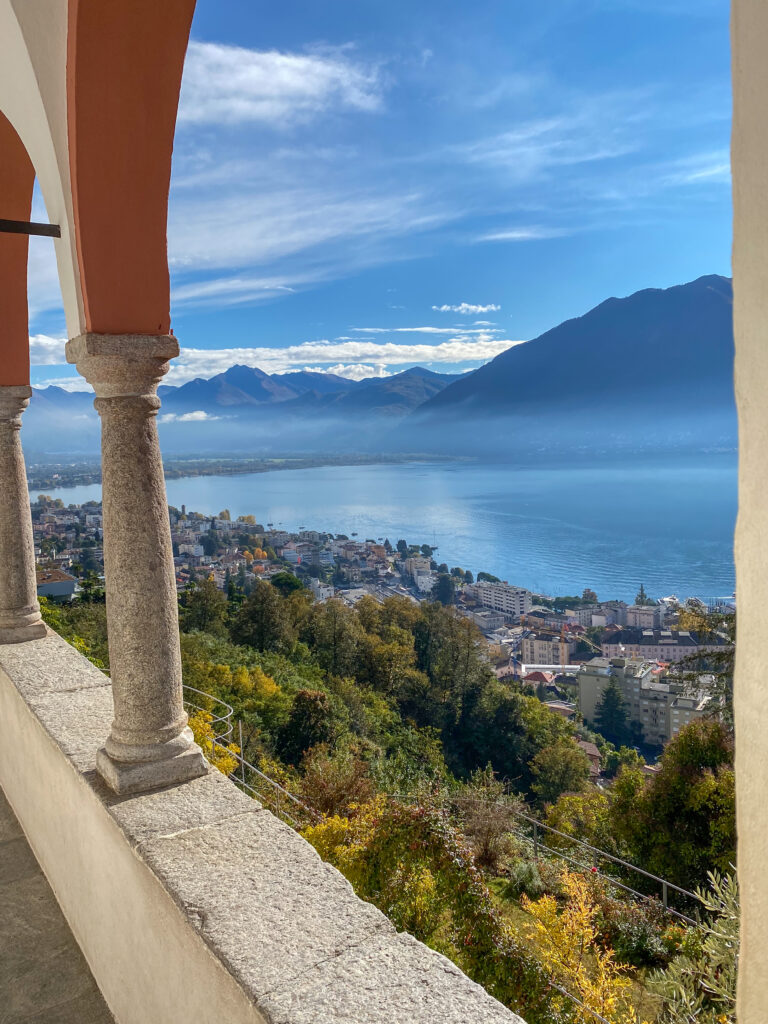 Balcon à arcades ouvrant sur un lac entouré de montagnes, ville en contrebas